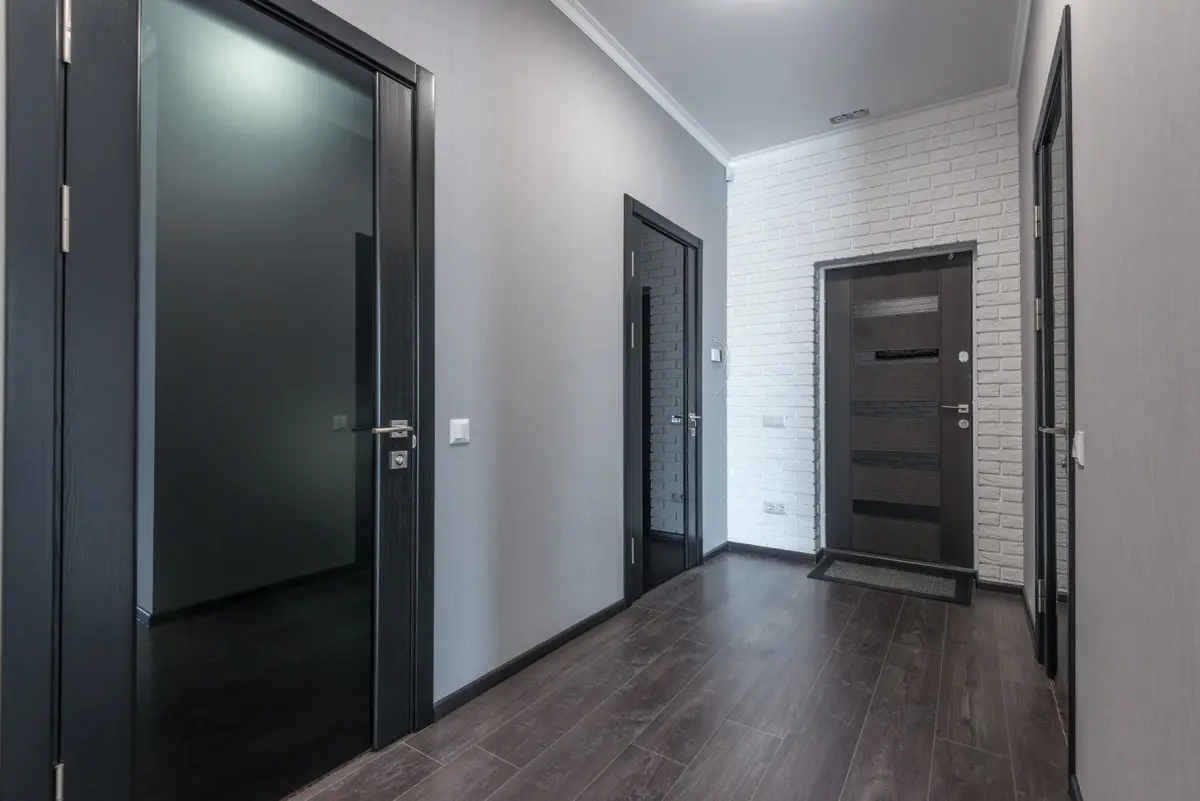 Gang in een appartementsgebouw met donkere deuren aan weerszijden