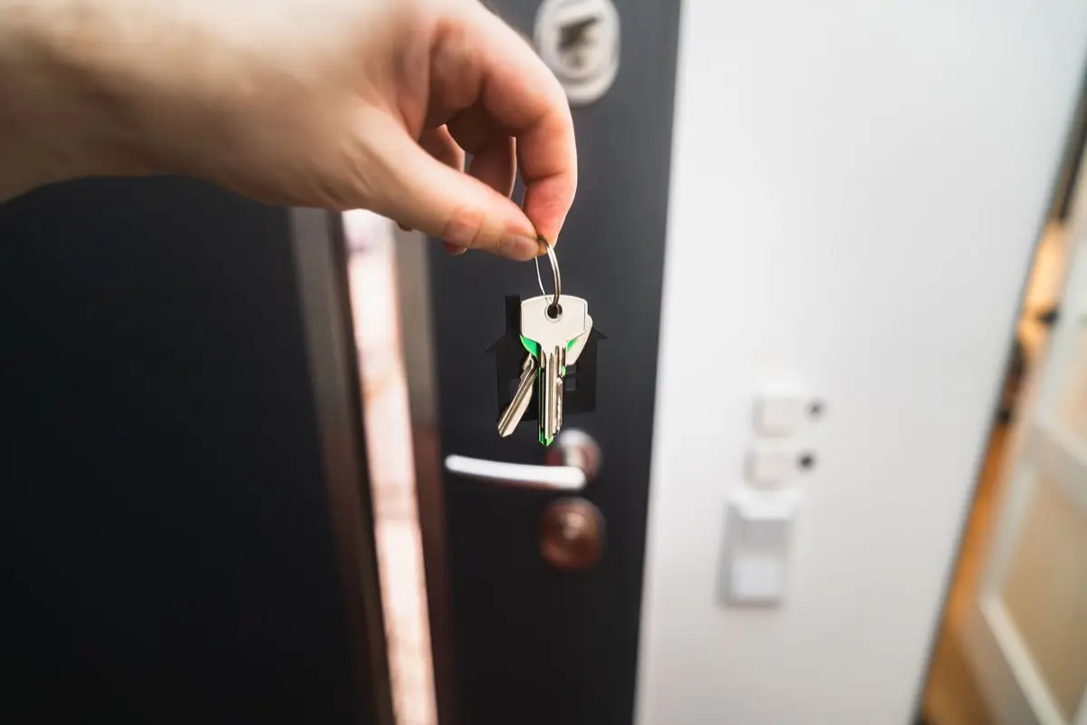 Hand met een sleutelbos voor een donkere voordeur met cilinderslot