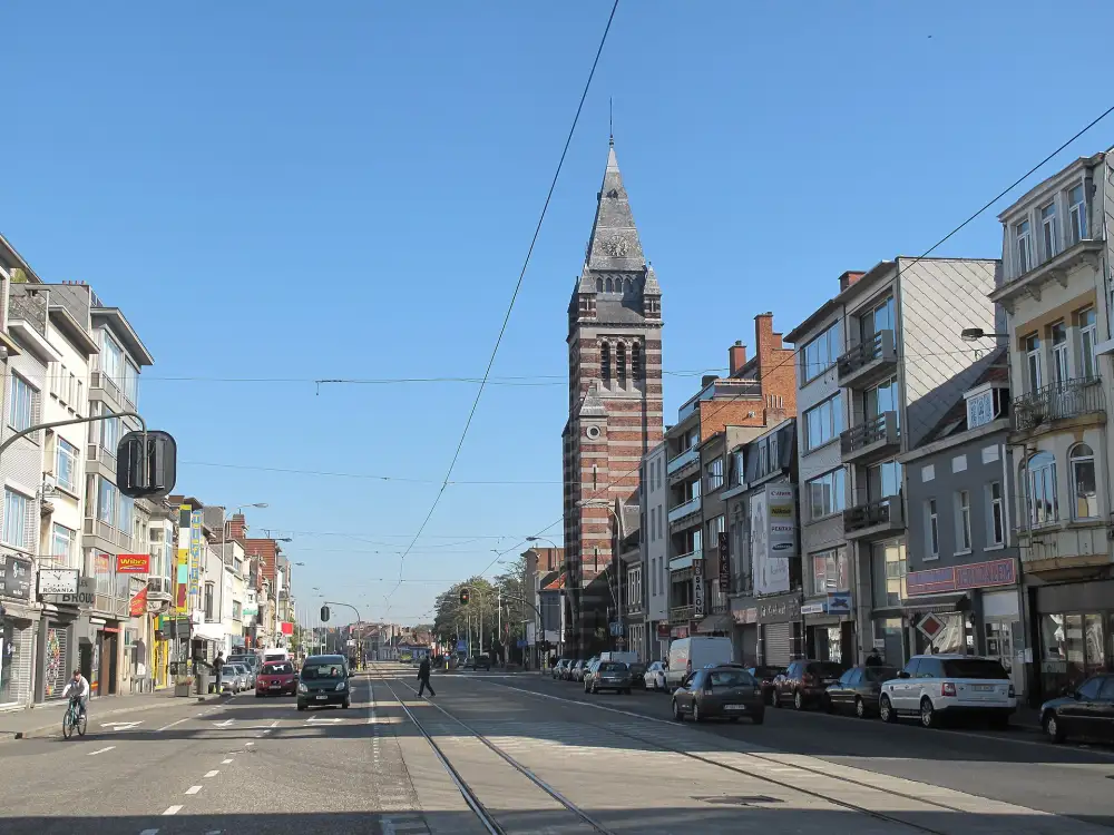 Straatzicht in Merksem met winkels, appartementen en de kerktoren